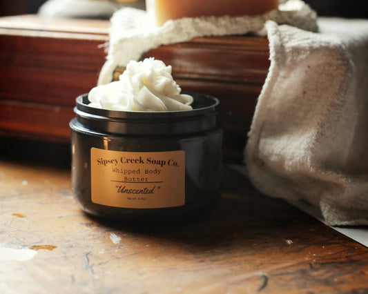A jar of whipped body butter from Sipsey Creek Soap Co. in unscented shown with its lid off.
